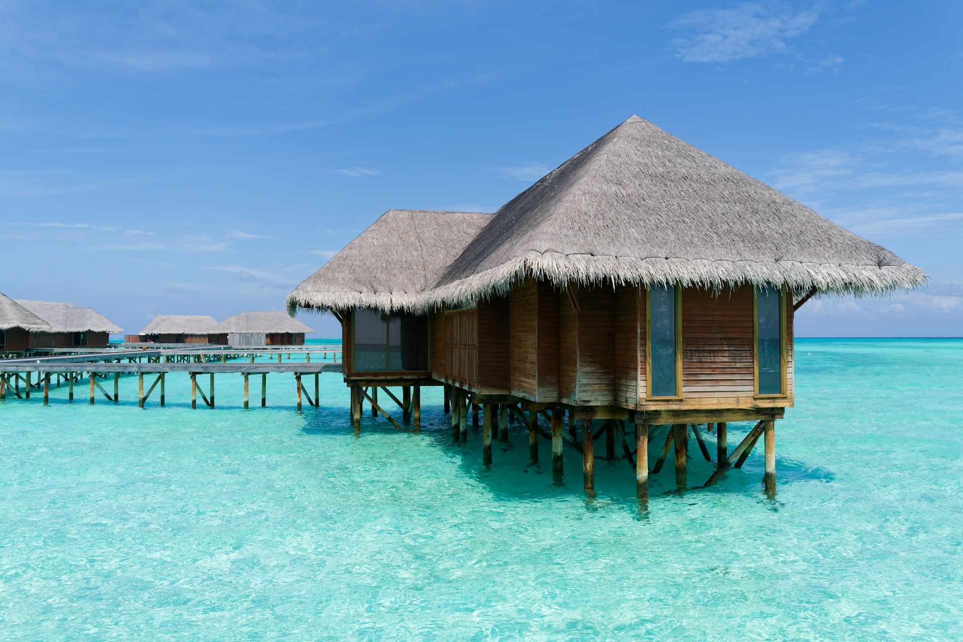 a house on stilts in the water near a pier