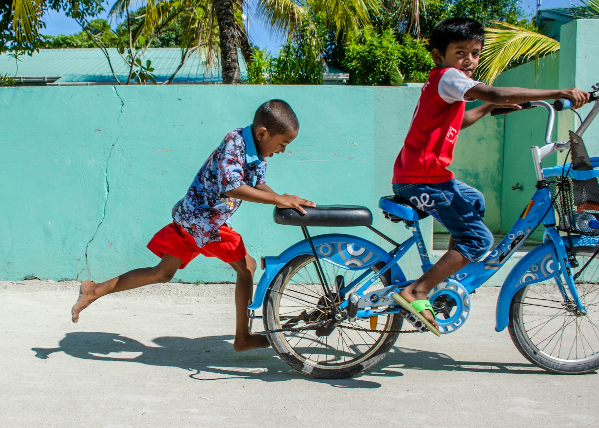 boy cycling near green wall during daytime